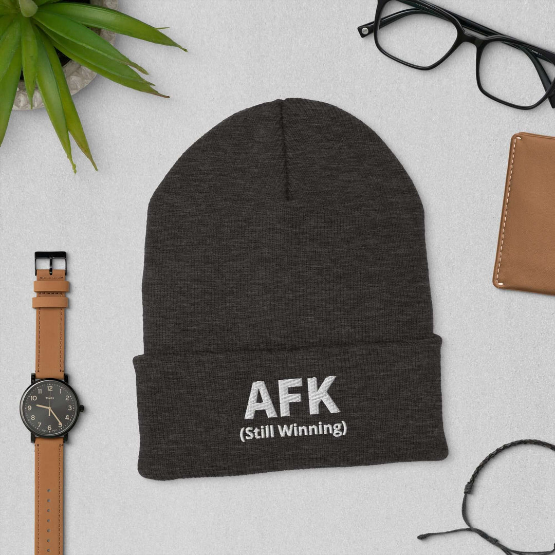 AFK Cuffed Beanie displayed with accessories on a table, featuring a snug design and stylish lettering.
